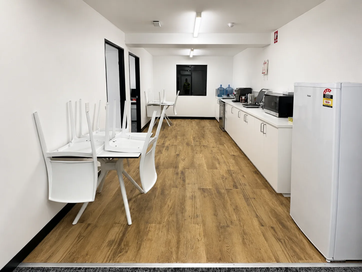 Commercial office lunchroom with white walls, timber-look flooring and a tidy kitchenette, freshly painted by Paint Gods.
