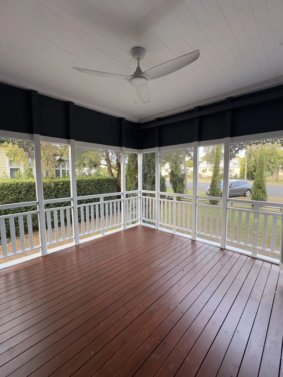 Timber verandah and deck with a white painted balustrade and ceiling, looking out over the garden, finished by Paint Gods.
