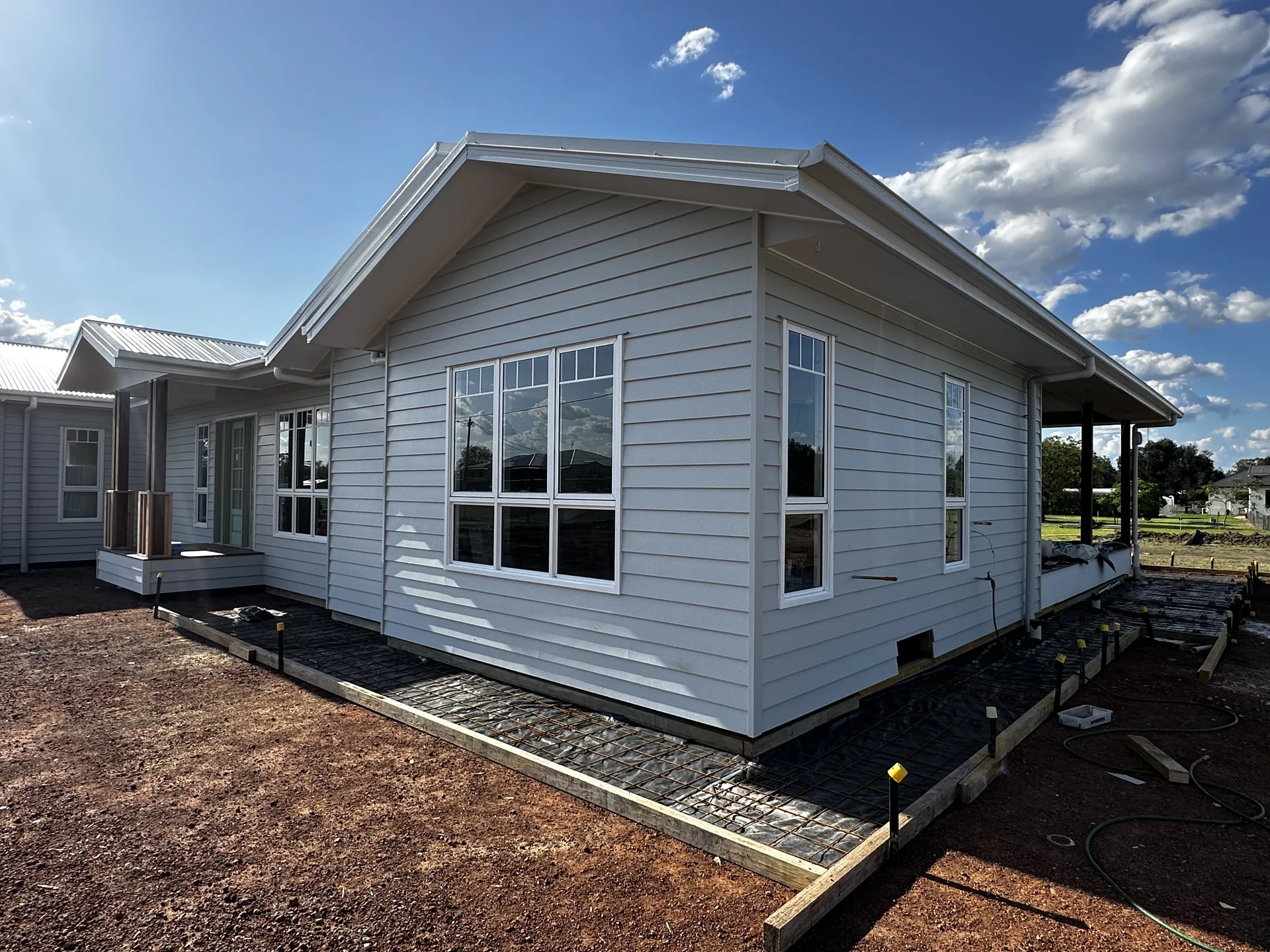 Freshly painted white weatherboard home with a gabled roofline and clean white trims, set against a clear blue sky.