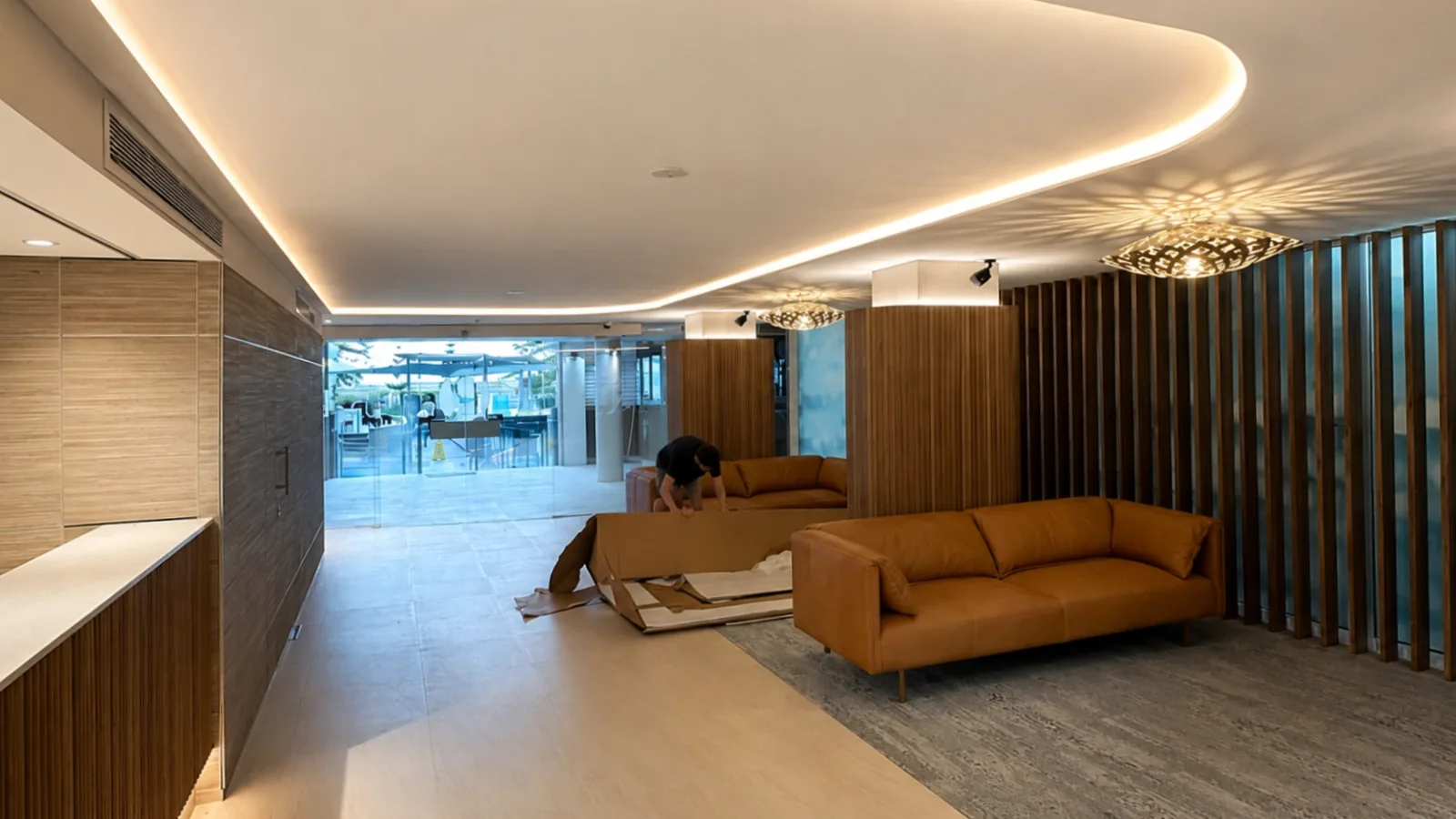 Rumba Resort lounge area in Caloundra with freshly painted ceilings and walls, warm lighting, timber wall panelling, tan leather sofas and a modern reception-style interior, showing commercial paint work by Paint Gods.