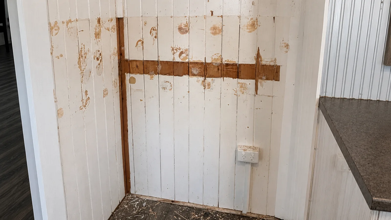 Before, interior vertical-board (VJ) wall with old, stained and patchy paintwork ready for restoration.