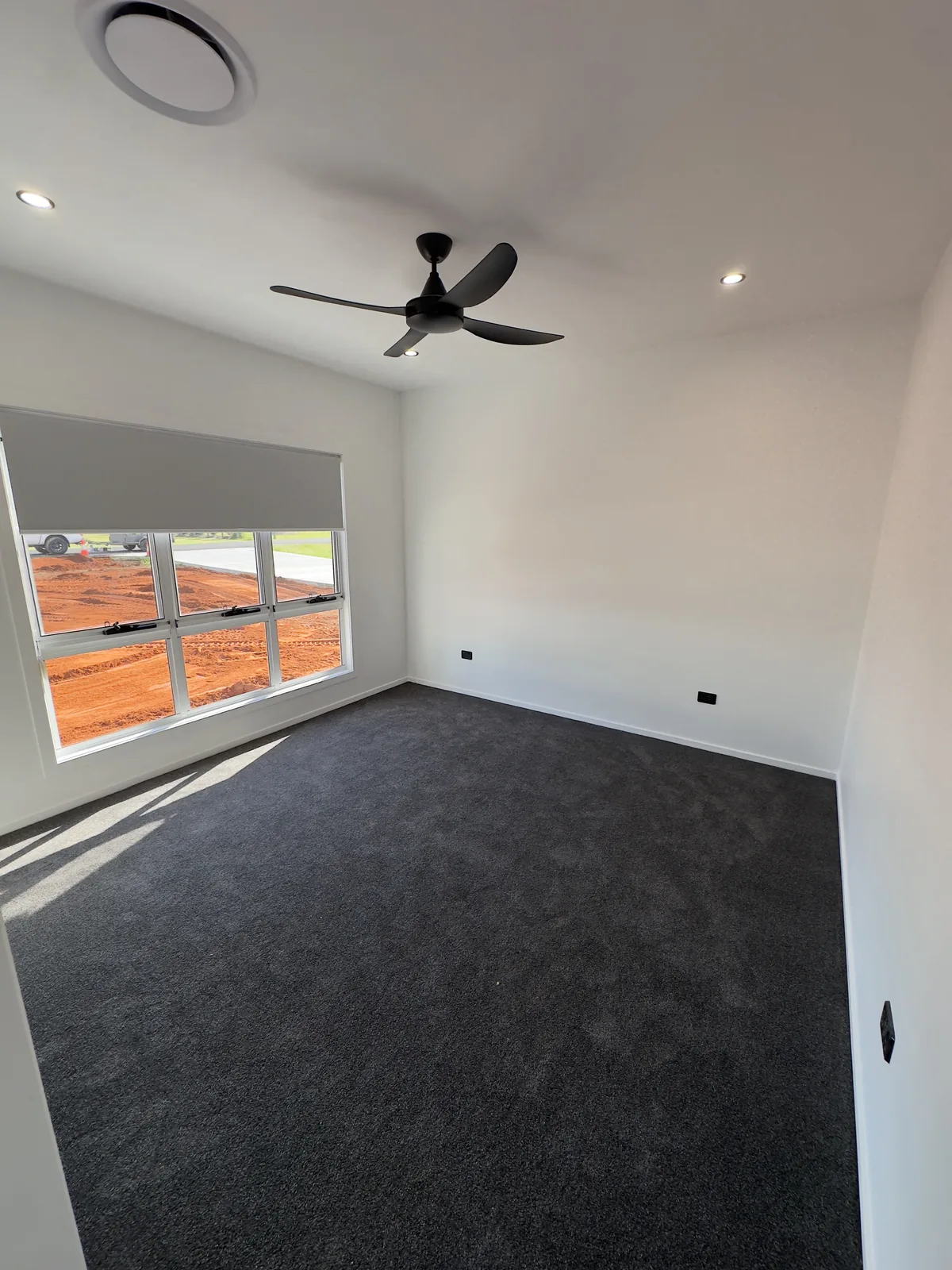Bedroom with crisp white walls and ceiling and a deep charcoal feature wall, with a black ceiling fan, painted by Paint Gods.