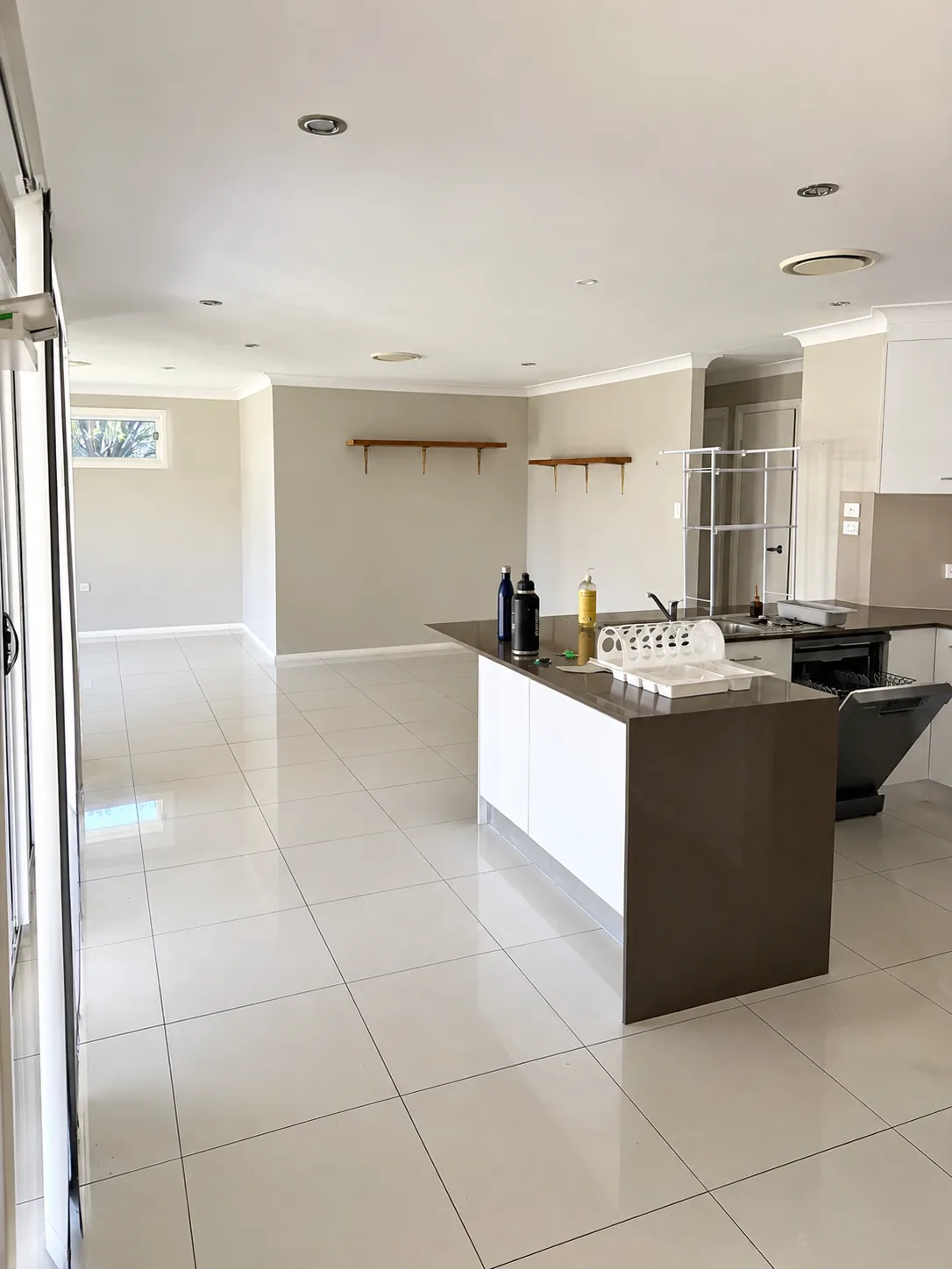 Open-plan home interior with crisp white walls and ceilings and a dark stone island bench, freshly painted throughout.